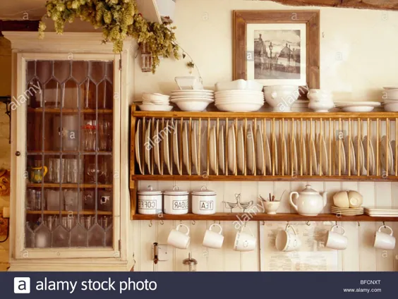 عکس - نزدیک نمایی از کاسه های کرم در صفحه قفسه های چوبی کنار کمد دیواری کوچک در آشپزخانه کلبه