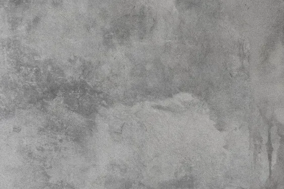 دیوار سیمانی بتونی خاکستری قدیمی با لکه های سفید و ترک های کوچک در سراسر بافت.
