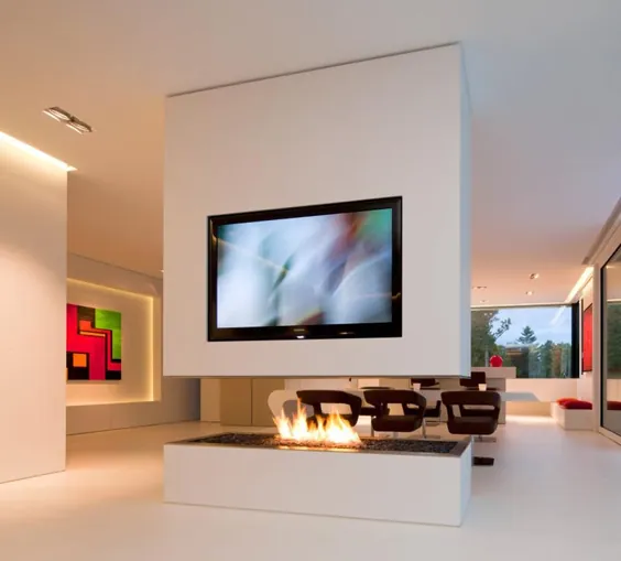 جداکننده اتاق مینیمالیست شامل تلویزیون و شومینه روباز در این خانه است