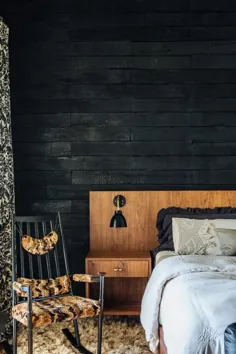 تختخواب کم نیم قرن در برابر دیوار چوبی سوخته
